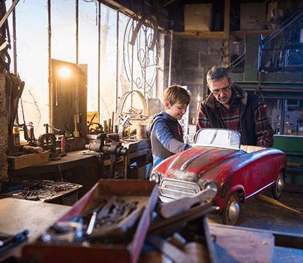 Grossvater und Enkel restaurieren Spielauto – Symbol für erfüllte Wünsche mit einem Konsumkredit